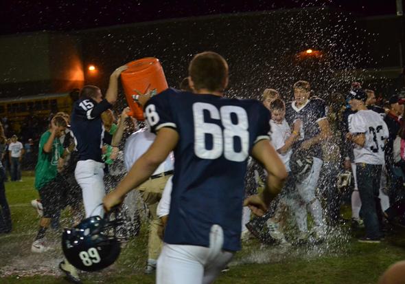 Varsity football players dump a cooler of water on coach Lindquist to celebrate their homecoming victory. (Photo by Kelsi Novitsky)